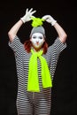 Portrait of female mime artist, isolated on black background. Young woman in striped clothes touching her funny bright Royalty Free Stock Photo
