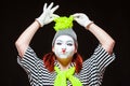 Portrait of female mime artist, isolated on black background. Young woman in striped clothes touching her funny bright Royalty Free Stock Photo