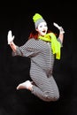 Portrait of female mime artist, isolated on black background. Young woman in striped suit and bright yellow scarf and Royalty Free Stock Photo