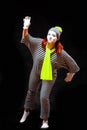 Portrait of female mime artist, isolated on black background. Young woman in striped suit and bright yellow scarf and Royalty Free Stock Photo