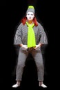 Portrait of female mime artist, isolated on black background. Young woman in striped suit and bright yellow scarf and Royalty Free Stock Photo