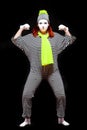 Portrait of female mime artist, isolated on black background. Young woman in striped suit and bright yellow scarf and Royalty Free Stock Photo