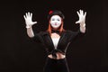 Portrait of female mime artist performing, isolated on black background. Woman is gesticulating with her hands looking Royalty Free Stock Photo