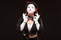 Portrait of female mime artist performing, isolated on black background. Woman is showing confidence touching her bow Royalty Free Stock Photo