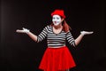 Portrait of female mime artist performing, isolated on black background. Woman is standing with her hands up. Symbol Royalty Free Stock Photo