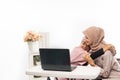 female muslim comforting her sad friend while working on her laptop