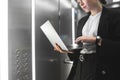 Portrait of a female office worker using her laptop in the elevator while being in a rush. Close up photo of busy businesswoman Royalty Free Stock Photo