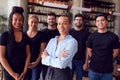 Portrait Of Female Owner Of Restaurant Bar With Team Of Waiting Staff Standing By Counter