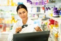 Portrait of female pharmacist working at the cash register in pharmacy - scans barcode on medicine package Royalty Free Stock Photo