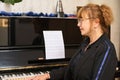 Portrait of a female pianist, music teacher sitting at grand piano in music classroom Royalty Free Stock Photo