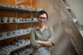 Female potter standing with arms crossed in pottery workshop