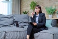 Portrait of female psychologist with clipboard sitting on couch in office Royalty Free Stock Photo