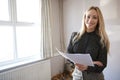 Portrait Of Female Realtor Looking At House Details In Property For Renovation