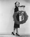 Portrait of female shopper with wreath and Christmas gifts