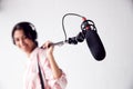 Portrait Of Female Sound Recordist Holding Microphone On Video Film Production In White Studio