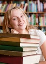 Portrait of a female student with pile books in library Royalty Free Stock Photo