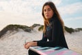 Portrait Of Female Surfer At The Beach Sitting On Sand Dunes Wearing A Wetsuit Royalty Free Stock Photo
