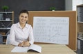 Portrait of happy young female teacher sitting at desk during her online math class Royalty Free Stock Photo