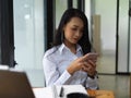 Female texting on smartphone while sitting at worktable in office room Royalty Free Stock Photo