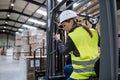 Female warehouse worker driving forklift. Warehouse worker preparing products for shipmennt, delivery, checking stock in Royalty Free Stock Photo