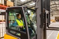 Female warehouse worker driving forklift. Warehouse worker preparing products for shipmennt, delivery, checking stock in Royalty Free Stock Photo
