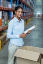 Portrait of female warehouse worker standing with clipboard Royalty Free Stock Photo