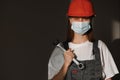 Portrait female worker is wear protection mask face, safety helmet and suit and with big screw key, wrench in hands. For working Royalty Free Stock Photo