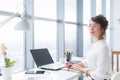 Portrait of a female writer working at office, using laptop, wearing glasses. Young employee planning her work day Royalty Free Stock Photo