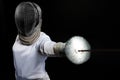 Portrait of fencer woman wearing white fencing costume practicing with the sword. Isolated on black background.