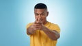 Portrait, finger gun and man aim at target in studio isolated on a blue background mockup space. Face, shooting hand