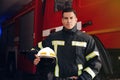 Portrait of firefighter in uniform with helmet near fire truck