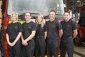 Portrait of firefighters standing by a fire engine