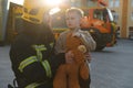 Portrait of a fireman and a little boy with a teddy bear. Royalty Free Stock Photo