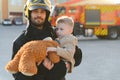 Portrait of a fireman and a little boy with a teddy bear. Royalty Free Stock Photo