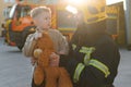 Portrait of a fireman and a little boy with a teddy bear. Royalty Free Stock Photo