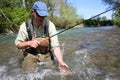 Portrait of fisherman in river catching brown trout