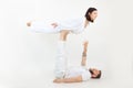 Fit family on white background. Middle-aged man lying, holding with legs young woman balancing, practicing acroyoga. Royalty Free Stock Photo