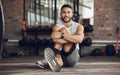 Portrait of fit man stretching before exercise. Young athlete stretching his leg before a workout. Handsome man doing a
