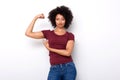 Fit young african woman pointing at arm muscles on white background