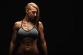 Portrait of a fit young woman posing wearing a sports bra against black background. Determined athlete in the studio