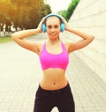 Portrait of fitness happy smiling young woman in headphones listening to music in the city Royalty Free Stock Photo