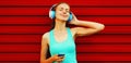 Portrait of fitness happy smiling young woman in headphones listening to music with smartphone on red background Royalty Free Stock Photo