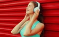 Portrait fitness smiling young woman in headphones listening to music on red background