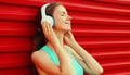 Portrait of fitness smiling young woman in headphones listening to music on red background Royalty Free Stock Photo