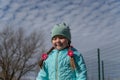 Portrait of a five-year-old girl in front of a cloudy sky. A child in a blue kurta with long pigtails. Childhood. Outside. A Royalty Free Stock Photo