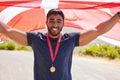 Portrait, flag and man with a medal for winner, sports competition or winner in the street. Happy, Denmark and a