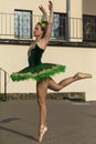 Portrait of Flying Professional Caucasian Ballerina in Green Tutu Dress and Artistic Flowery Crown Ourdoors