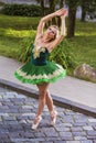 Portrait of Flying Professional Caucasian Ballerina in Green Tutu Dress With Lifted Hands Ourdoors