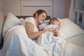 Portrait fo smiling young mother lying in bed with her 9 months old baby boy Royalty Free Stock Photo