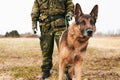 Portrait, focus and german shepherd or service dog or security in uniform and male soldier with puppy on leash outdoors Royalty Free Stock Photo